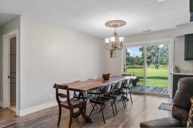 dining area featuring wood-type flooring, a textured ceiling, and a notable chandelier