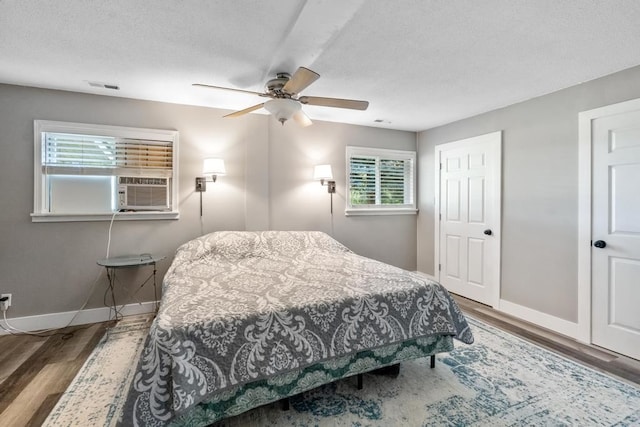 bedroom featuring ceiling fan, hardwood / wood-style floors, and a textured ceiling