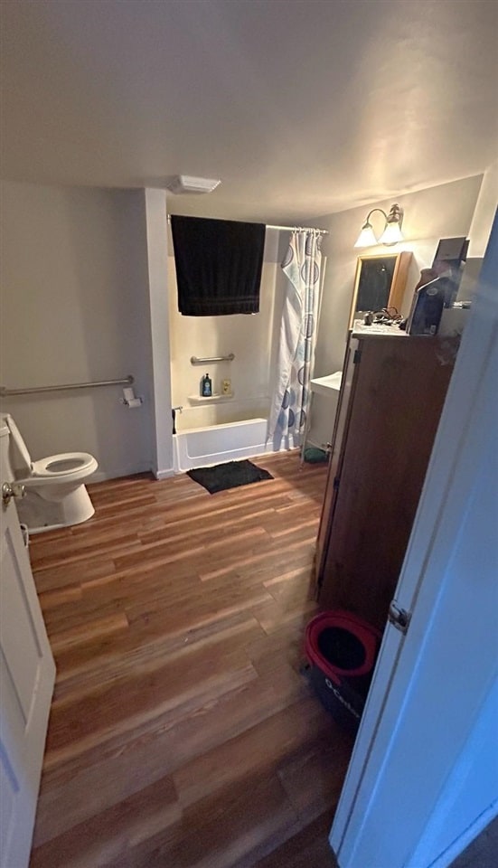 full bathroom featuring hardwood / wood-style floors, vanity, toilet, and shower / bath combo with shower curtain