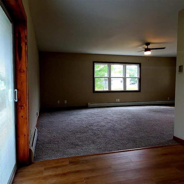 empty room featuring hardwood / wood-style flooring, ceiling fan, and a baseboard heating unit