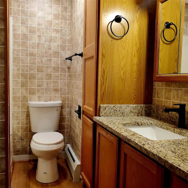 bathroom with hardwood / wood-style floors, a baseboard radiator, toilet, and tile walls