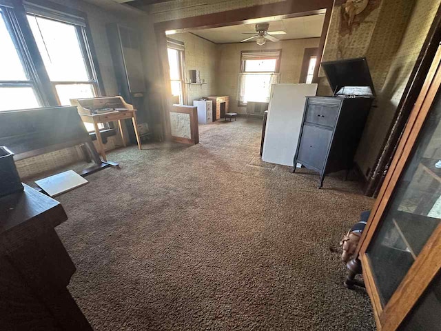 interior space with dark carpet and ceiling fan