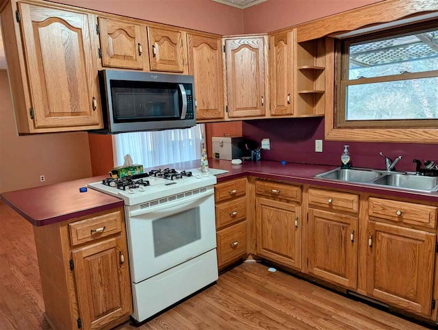 kitchen with white gas stove, sink, and light hardwood / wood-style flooring