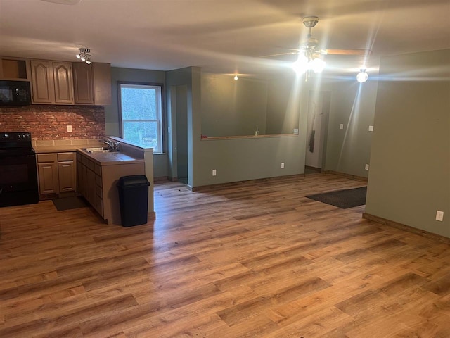 kitchen featuring backsplash, sink, black appliances, and hardwood / wood-style flooring