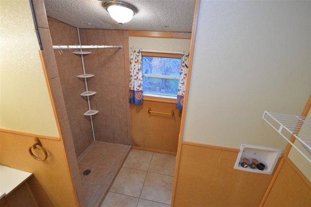 bathroom with wood walls, tile patterned flooring, a textured ceiling, and tiled shower