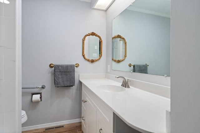 bathroom featuring wood-type flooring, vanity, toilet, and ornamental molding
