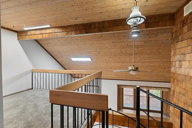 hallway featuring carpet, lofted ceiling, wood walls, and wooden ceiling