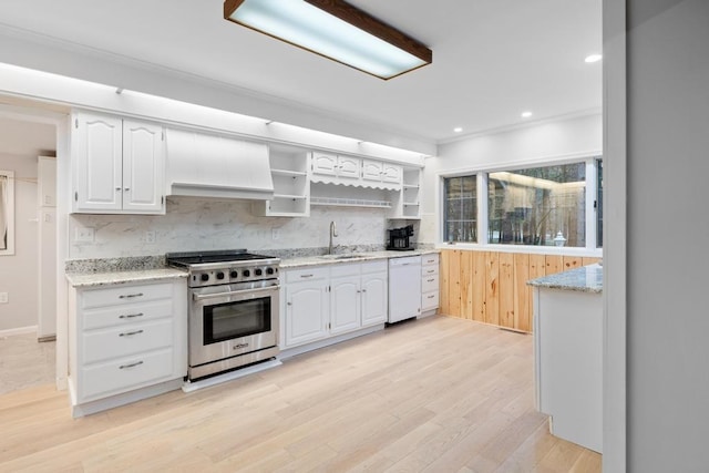 kitchen with light wood-type flooring, high end stove, white cabinetry, and sink