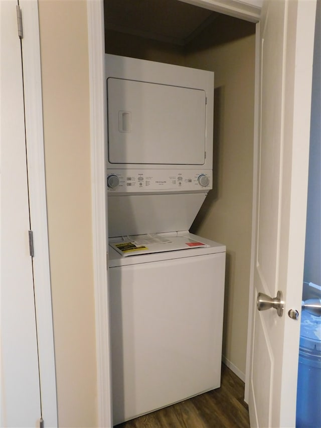 clothes washing area with stacked washer and dryer and dark wood-type flooring