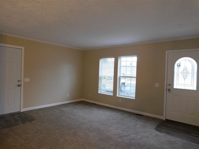 entryway featuring a textured ceiling, dark carpet, and crown molding