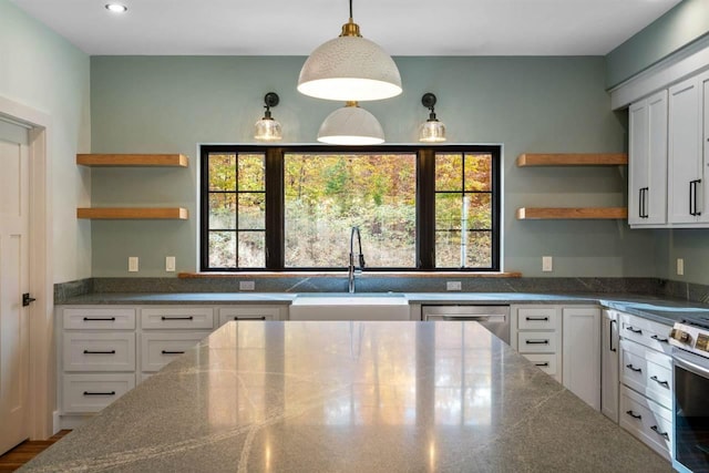 kitchen with white cabinets, a healthy amount of sunlight, dark stone countertops, and sink