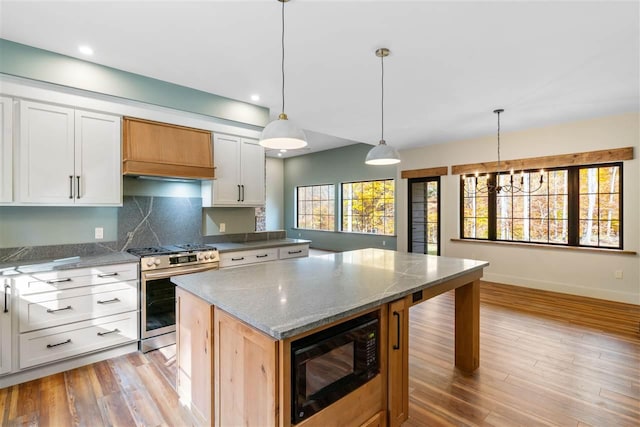 kitchen featuring black microwave, white cabinetry, stainless steel range, and a healthy amount of sunlight