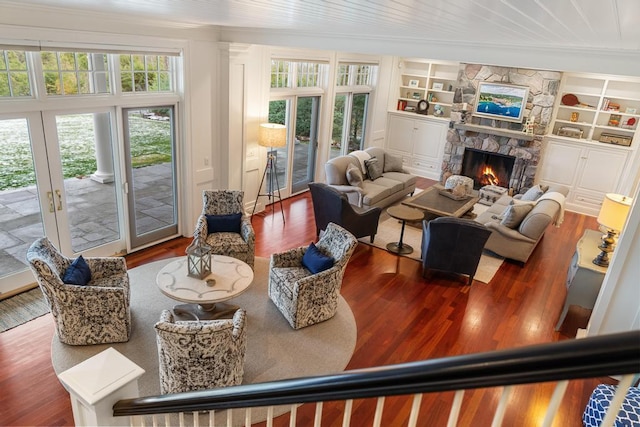 living room featuring a fireplace, hardwood / wood-style floors, built in features, and french doors