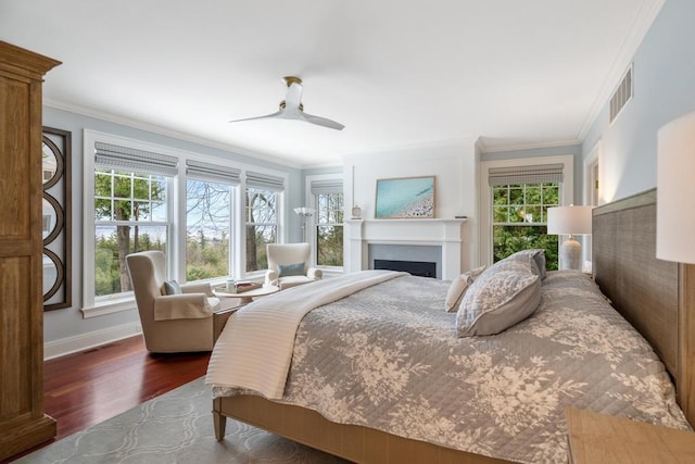 bedroom featuring ceiling fan, crown molding, dark wood-type flooring, and multiple windows