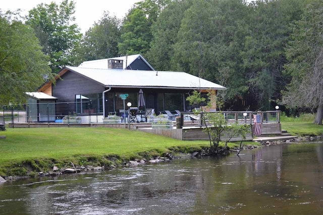 back of property with a water view and a yard