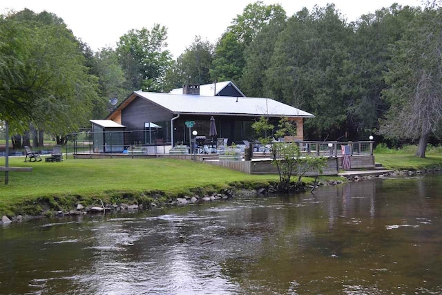 rear view of house with a yard and a water view