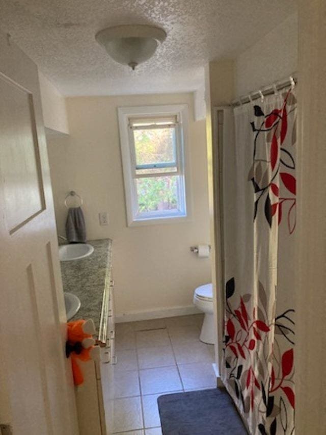 bathroom with tile patterned floors, vanity, a textured ceiling, and toilet