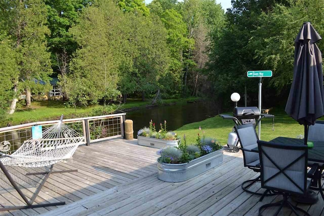 wooden deck with a lawn and a water view