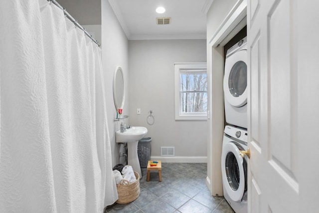 laundry area with laundry area, light tile patterned floors, visible vents, stacked washer / dryer, and crown molding