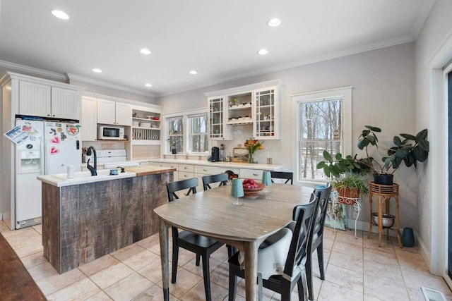 kitchen featuring tasteful backsplash, crown molding, an island with sink, white appliances, and white cabinets