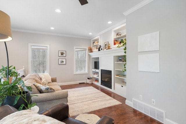 living area with dark wood-style floors, plenty of natural light, visible vents, and ornamental molding