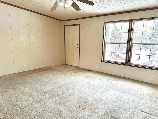 spare room featuring ceiling fan, crown molding, light carpet, and a textured ceiling