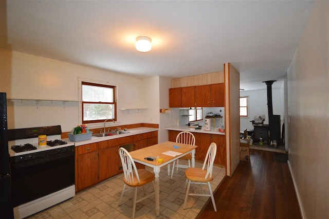 kitchen featuring light wood-type flooring, a wood stove, gas range gas stove, and sink