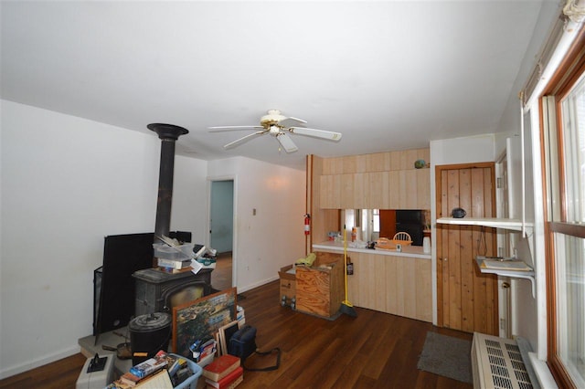 kitchen featuring light brown cabinets, dark hardwood / wood-style flooring, a wood stove, and ceiling fan