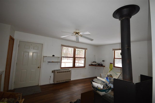 interior space with radiator, dark hardwood / wood-style floors, a wood stove, and ceiling fan