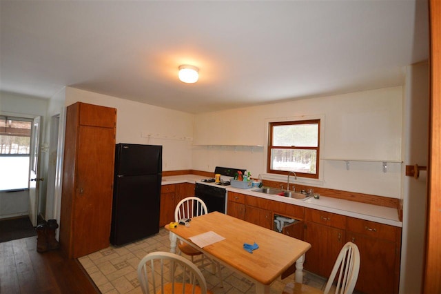 kitchen with black refrigerator, white range, light hardwood / wood-style floors, and sink