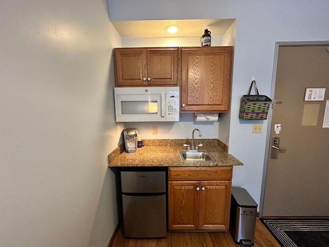 kitchen featuring stainless steel refrigerator, sink, dark wood-type flooring, and stone countertops