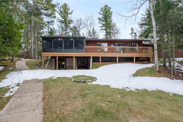 view of front of property with a front yard, a wooden deck, and a sunroom