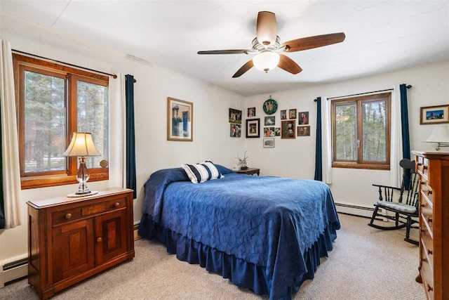 carpeted bedroom featuring baseboard heating, multiple windows, and ceiling fan