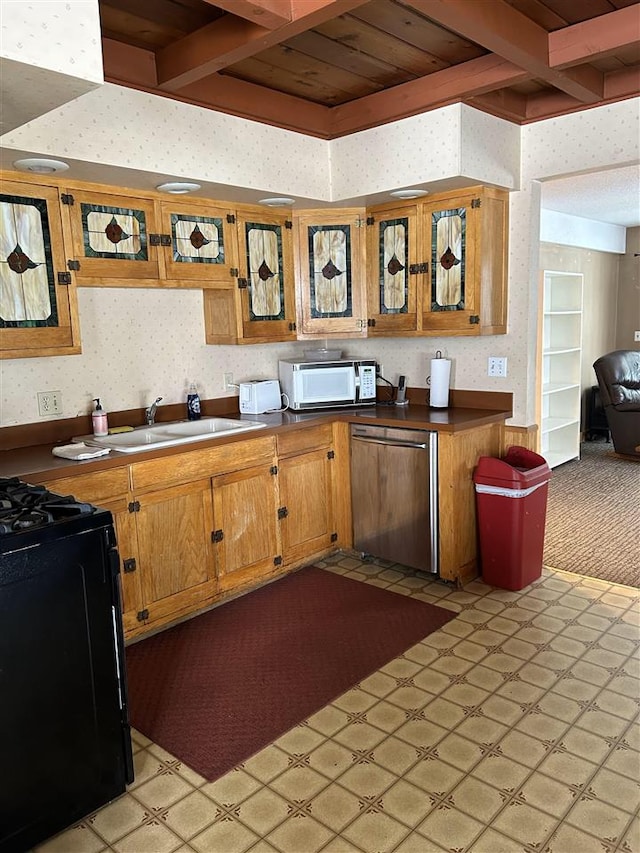 kitchen with beam ceiling, sink, black range oven, and stainless steel dishwasher