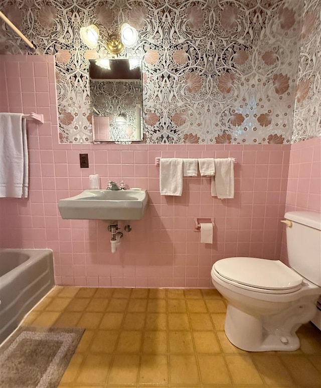 bathroom with sink, toilet, and tile walls