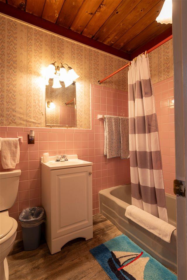 full bathroom featuring wood-type flooring, toilet, tile walls, and shower / bath combination with curtain