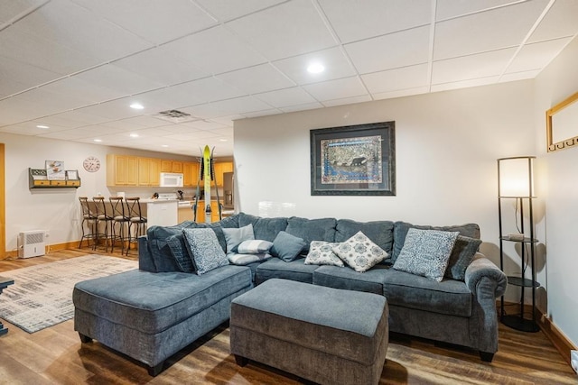 living room with a paneled ceiling and hardwood / wood-style flooring