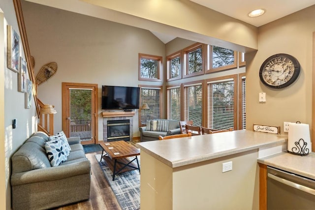 living room featuring a tile fireplace, high vaulted ceiling, and dark hardwood / wood-style floors