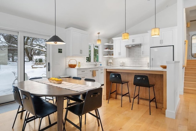 kitchen with decorative backsplash, white appliances, decorative light fixtures, white cabinetry, and lofted ceiling