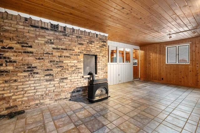 unfurnished living room with brick wall, a wood stove, wooden ceiling, and wood walls