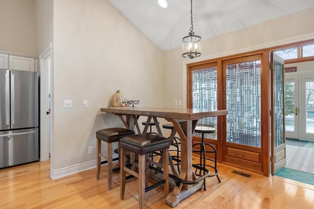 dining room featuring french doors, high vaulted ceiling, an inviting chandelier, and light hardwood / wood-style flooring