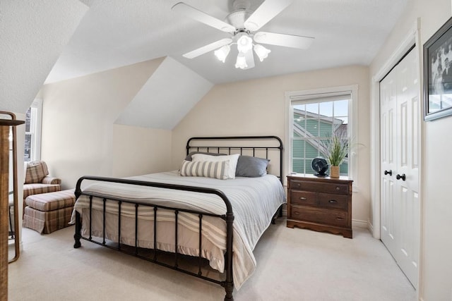 bedroom featuring a closet, light colored carpet, vaulted ceiling, and ceiling fan