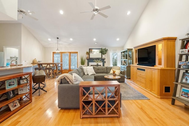 living room with ceiling fan, light hardwood / wood-style flooring, high vaulted ceiling, and french doors