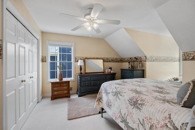 carpeted bedroom with ceiling fan, a closet, and vaulted ceiling