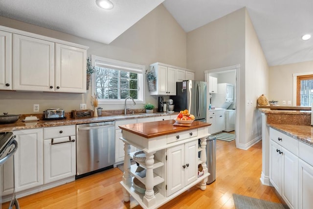 kitchen with sink, stainless steel appliances, white cabinetry, and light hardwood / wood-style flooring