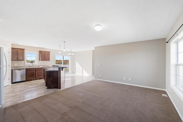 kitchen featuring light carpet, a kitchen island, hanging light fixtures, and stainless steel dishwasher