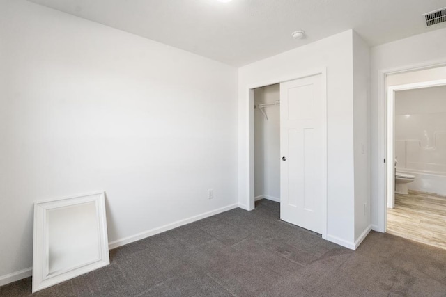 unfurnished bedroom featuring dark colored carpet and a closet