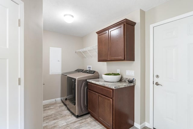 washroom with cabinets, electric panel, light hardwood / wood-style floors, and washer and clothes dryer