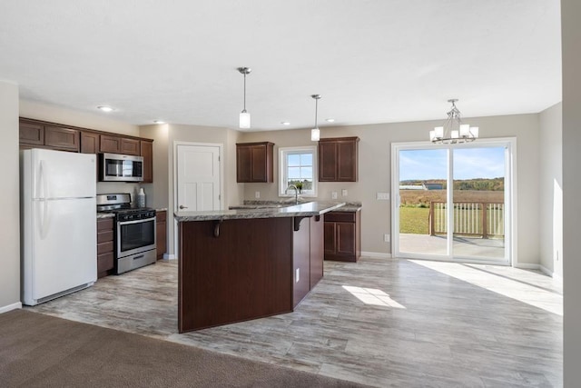 kitchen featuring a center island, pendant lighting, a chandelier, a breakfast bar area, and appliances with stainless steel finishes