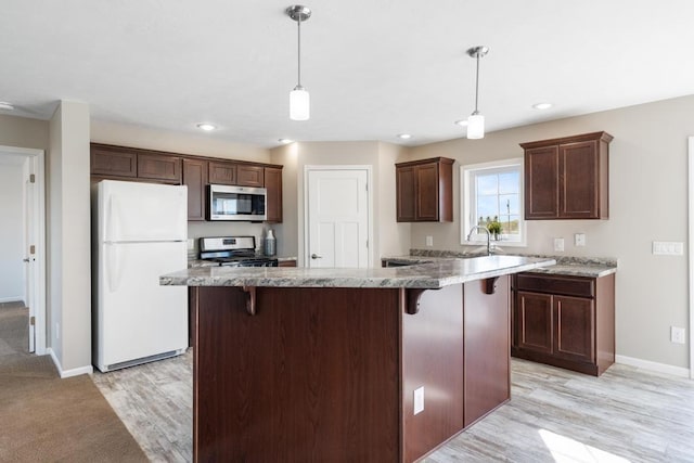 kitchen featuring a center island, pendant lighting, a breakfast bar area, appliances with stainless steel finishes, and light wood-type flooring